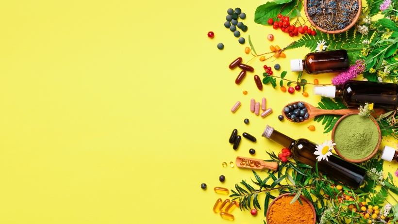 Auf der rechten Seite werden vor einem leuchtend gelben Hintergrund verschiedene Kräuterergänzungsmittel, Öle und natürliche Inhaltsstoffe zur Förderung der Gesundheit und veganen Ernährung angezeigt.